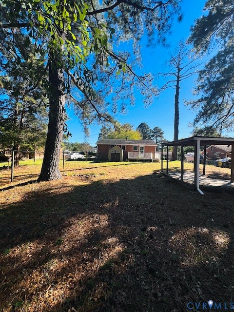 Expansive backyard featuring mature pine trees, a detached open-air shelter, and a fenced perimeter