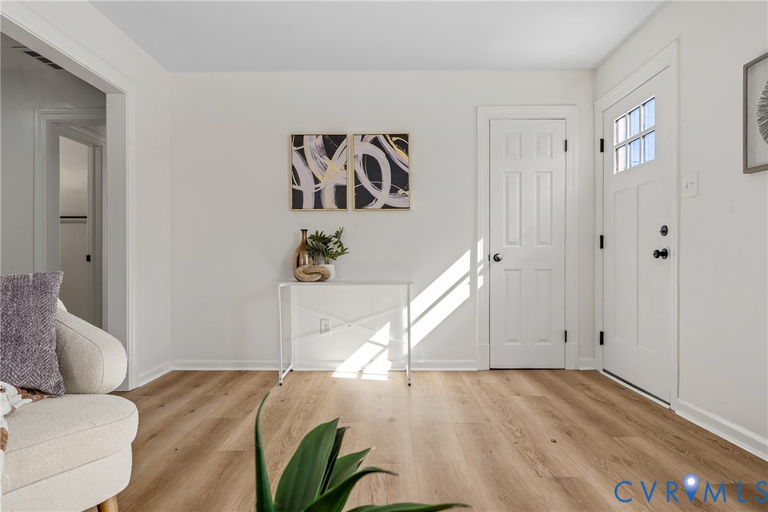 Entryway featuring wood-finish flooring, a six-panel door with a multi-pane glass insert, and neutral wall tones Entryway featuring wood-finish flooring, a six-panel door with a multi-pane glass insert, and neutral wall tones
