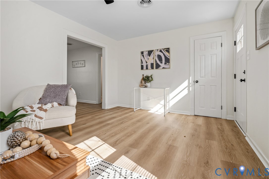Neutral-toned interior featuring wood-finish flooring, a six-panel door, and a front entry door with integrated glass panes Neutral-toned interior featuring wood-finish flooring, a six-panel door, and a front entry door with integrated glass panes