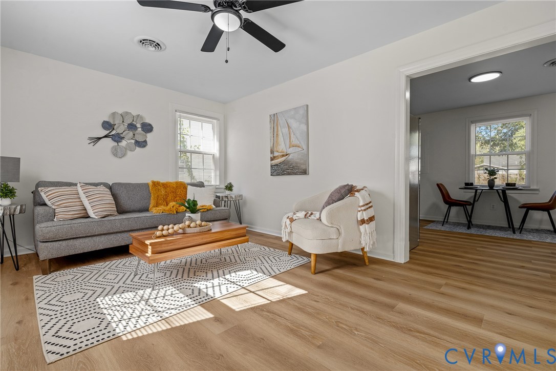 Living area featuring wood-finish flooring, a ceiling fan with integrated lighting, and multiple windows Living area featuring wood-finish flooring, a ceiling fan with integrated lighting, and multiple windows