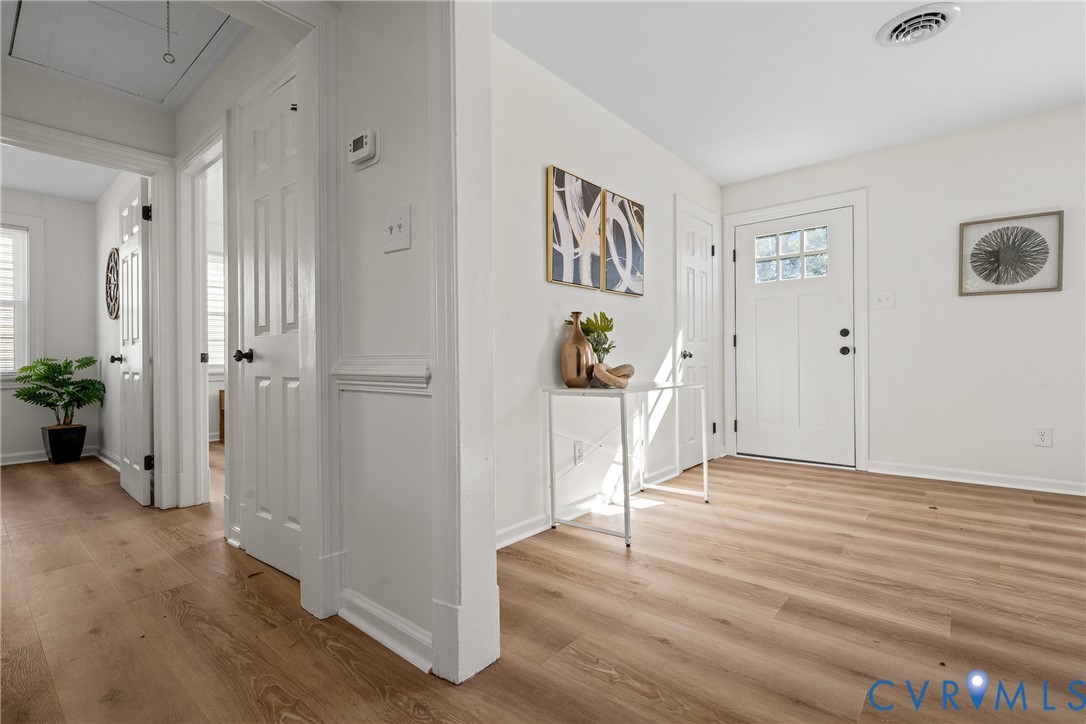 Entryway featuring wood-finish flooring, white panel doors, chair rail molding, and a front door with glass pane detail