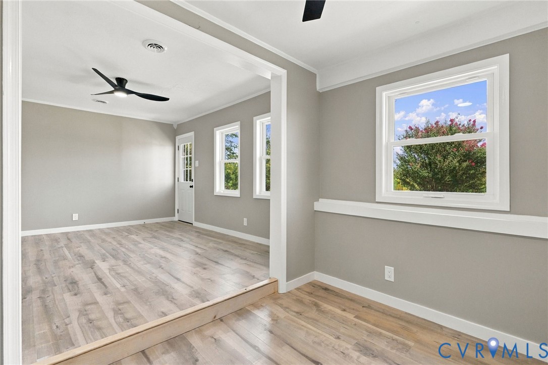 Neutral-toned walls featuring crisp white wainscoting and trim, wood-finish flooring, recessed lighting, and matte black ceiling fans Neutral-toned walls featuring crisp white wainscoting and trim, wood-finish flooring, recessed lighting, and matte black ceiling fans