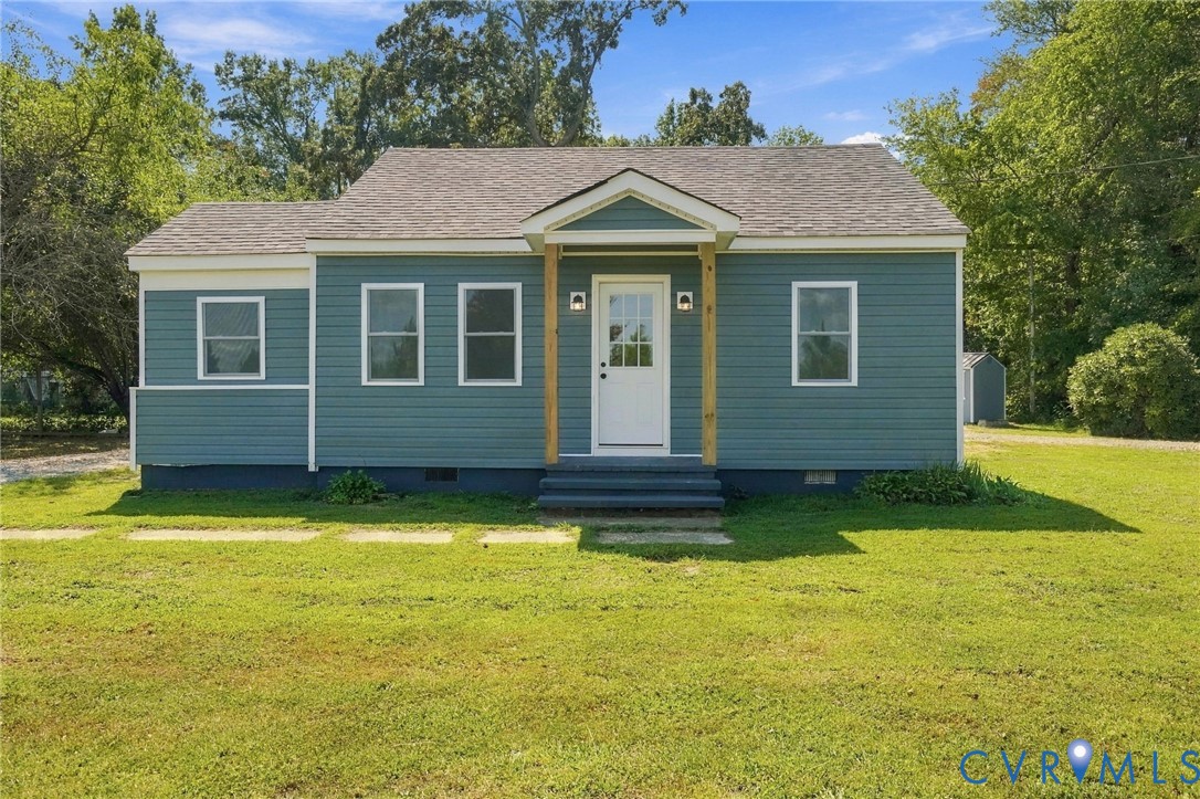 Single-story residence featuring blue horizontal siding, a gabled covered entryway with wooden support posts, and multi-pane windows Single-story residence featuring blue horizontal siding, a gabled covered entryway with wooden support posts, and multi-pane windows