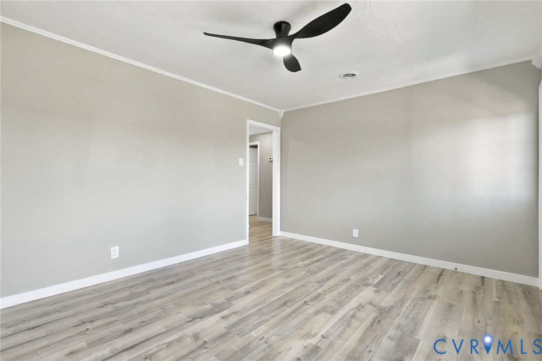 Neutral grey interior walls, wood-finish flooring, and a modern three-blade ceiling fan with integrated lighting Neutral grey interior walls, wood-finish flooring, and a modern three-blade ceiling fan with integrated lighting