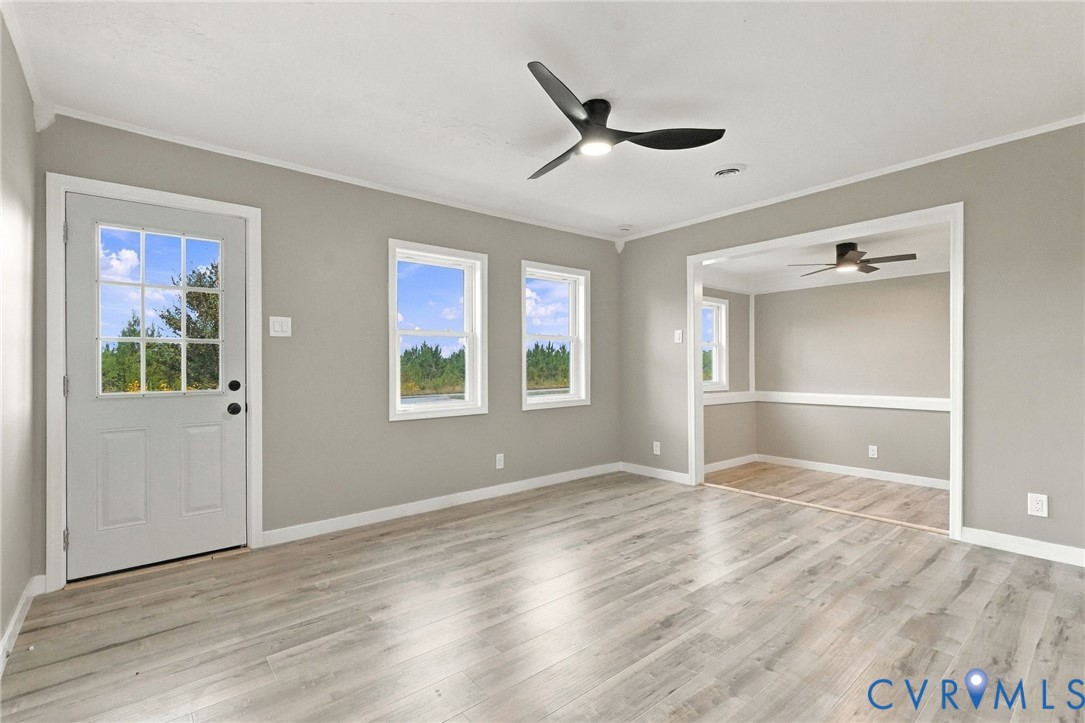 Neutral-toned walls, wood-finish flooring, multi-light glass panel door, matte black ceiling fans, and wainscoting detailing Neutral-toned walls, wood-finish flooring, multi-light glass panel door, matte black ceiling fans, and wainscoting detailing