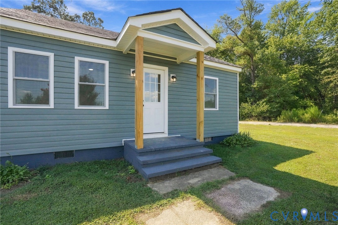 Exterior featuring blue horizontal siding, a covered entryway with wood-finish support columns, a gabled roofline, and concrete steps Exterior featuring blue horizontal siding, a covered entryway with wood-finish support columns, a gabled roofline, and concrete steps