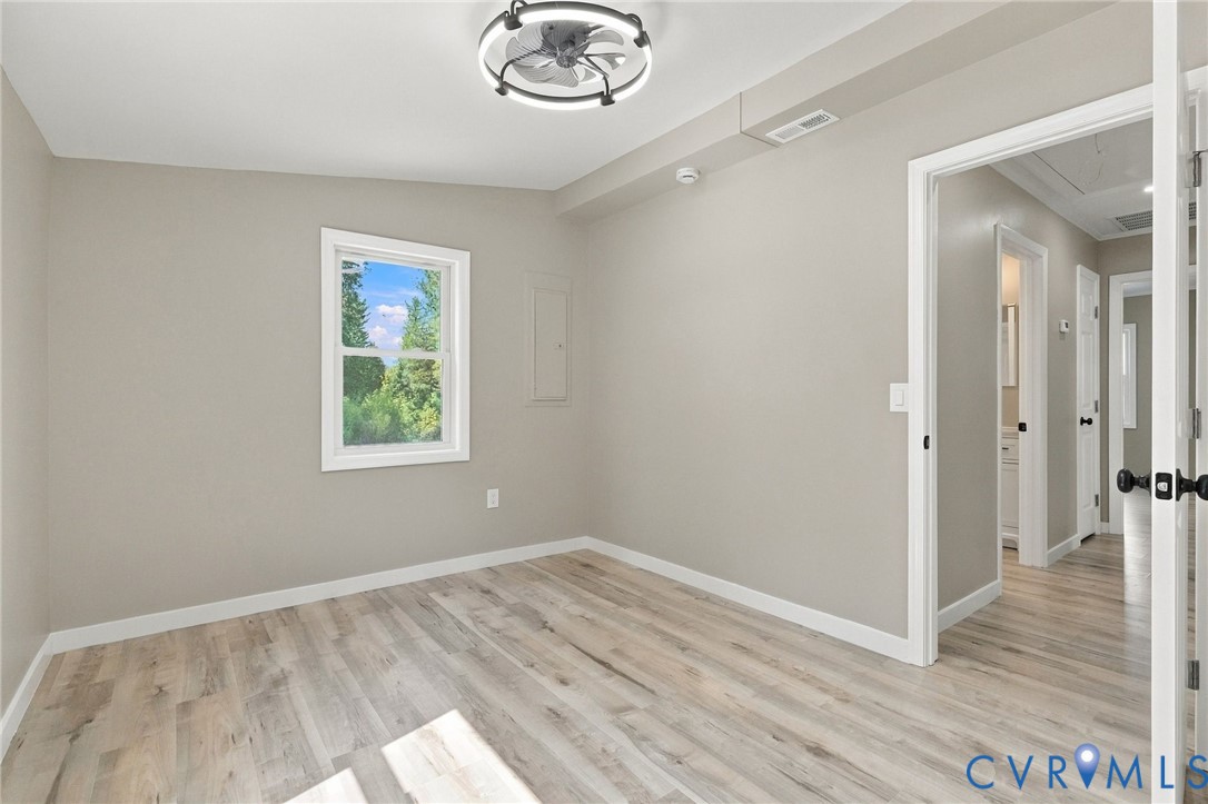 Interior space featuring neutral wall paint, wood-finish flooring, a contemporary cage-style ceiling fan with integrated lighting, and a single-hung window