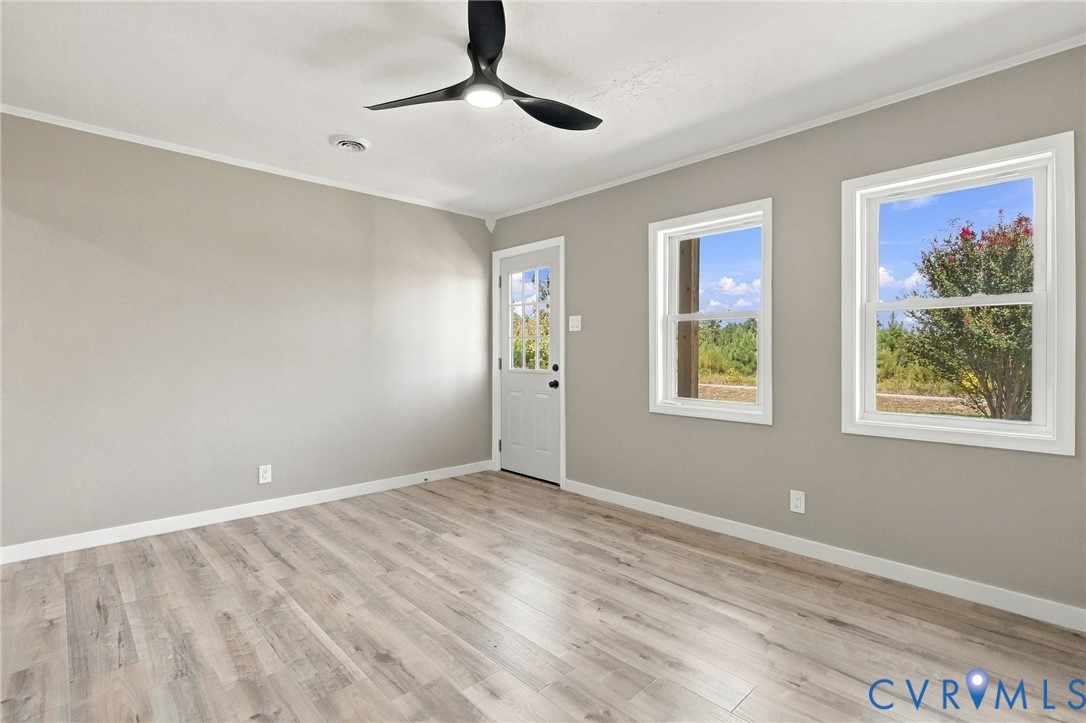 Neutral-toned interior space featuring wood-finish flooring, dual-pane windows, a contemporary matte black ceiling fan, and a glass-paneled exterior door Neutral-toned interior space featuring wood-finish flooring, dual-pane windows, a contemporary matte black ceiling fan, and a glass-paneled exterior door