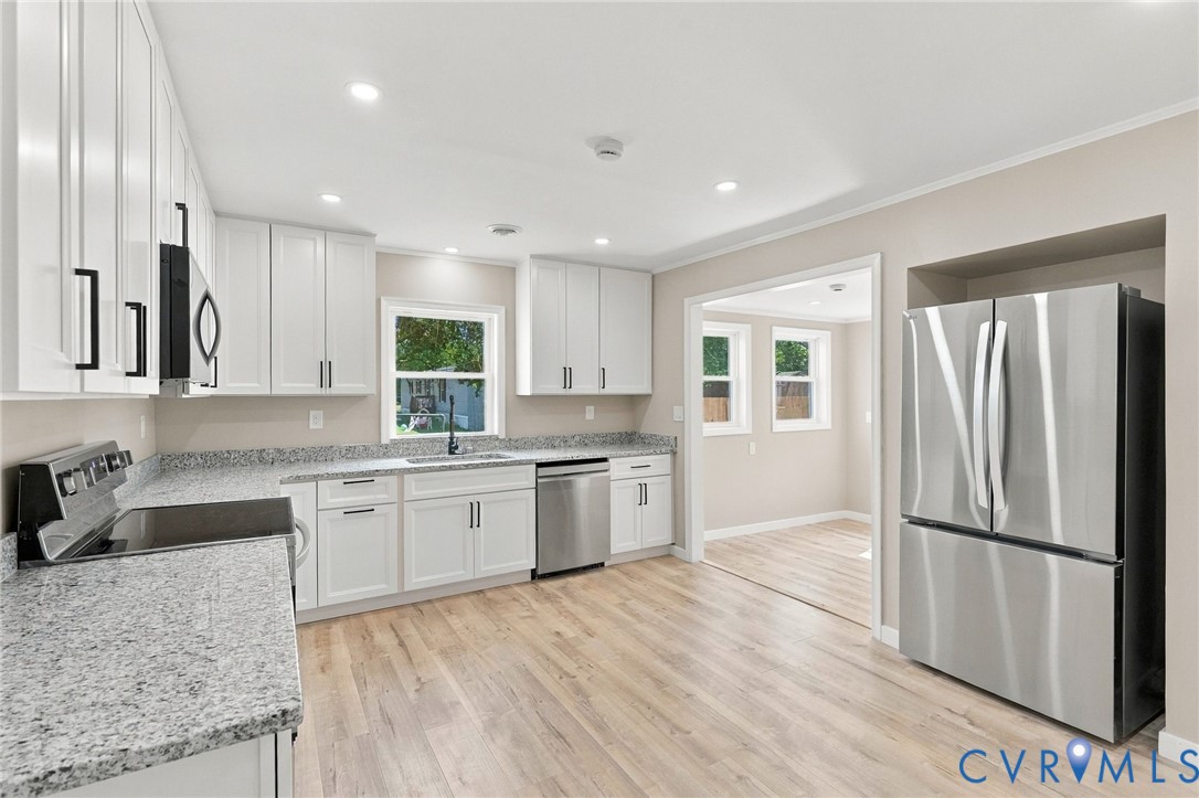 Kitchen featuring white shaker-style cabinetry, stone-finish countertops, stainless steel appliances, recessed lighting, and wood-finish flooring