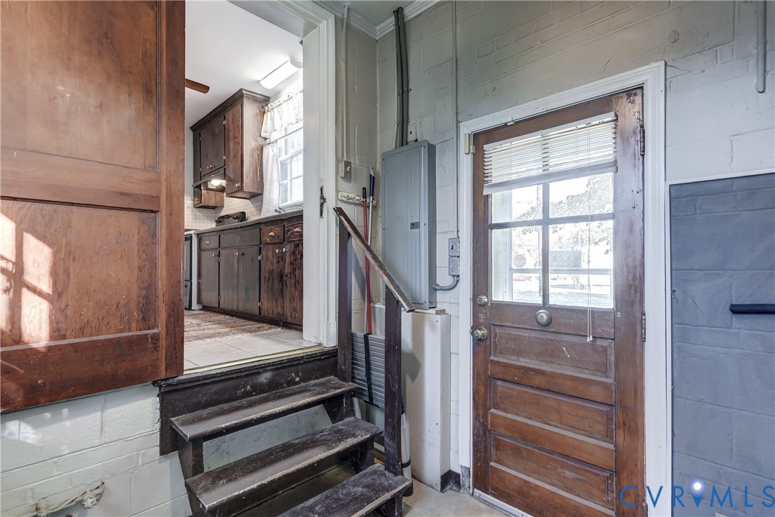 Exterior wood door featuring a glass pane, wood-finish interior door, stairs with wooden treads and railing, and painted masonry wall finish