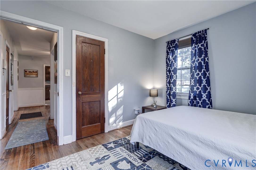 Interior room featuring wood-finish flooring, a solid wood-panel door, and a single-hung window