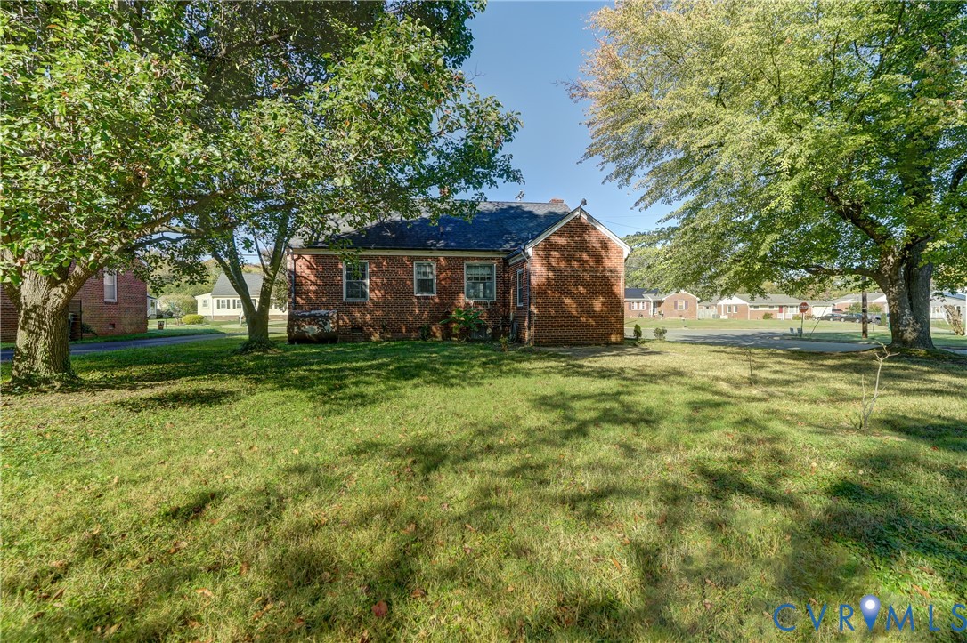 Brick exterior featuring a multi-gabled roofline and mature hardwood trees on the grounds