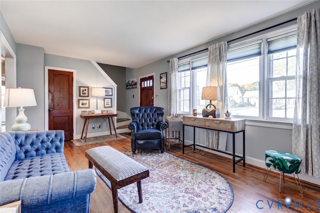 Living area featuring wood-finish flooring, multi-pane windows, and a classic paneled wood door