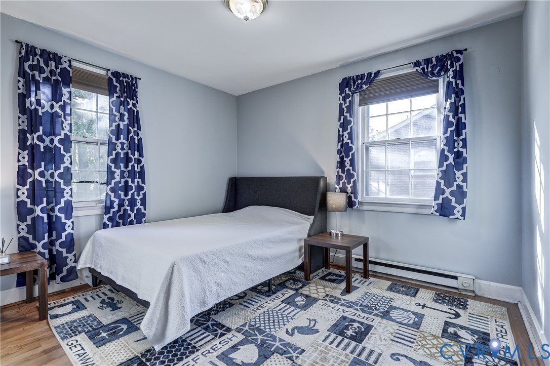 Room with wood-finish flooring, two windows with double-hung glass panes, and a flush-mount ceiling light fixture