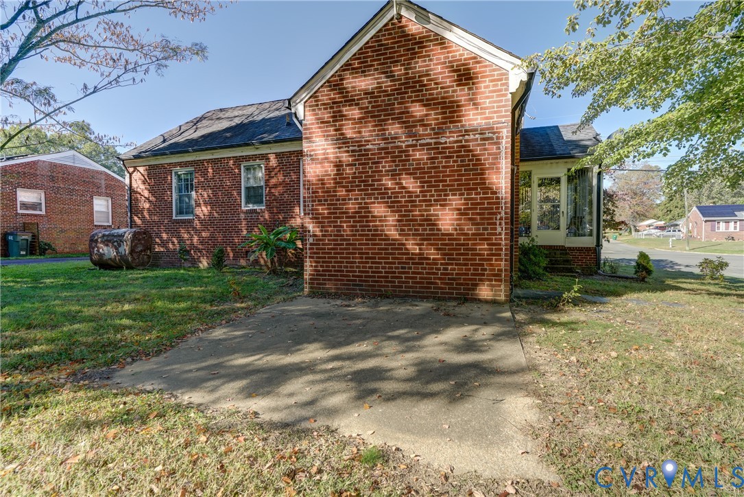 Brick exterior with a concrete patio, multi-pane windows, and a glass-paneled entry door