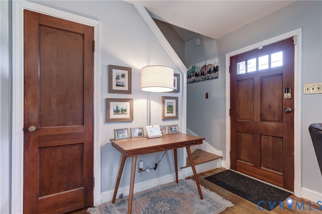 Entryway featuring a solid wood door with multi-pane transom glass, traditional wood-finish interior door, and wood-finish flooring