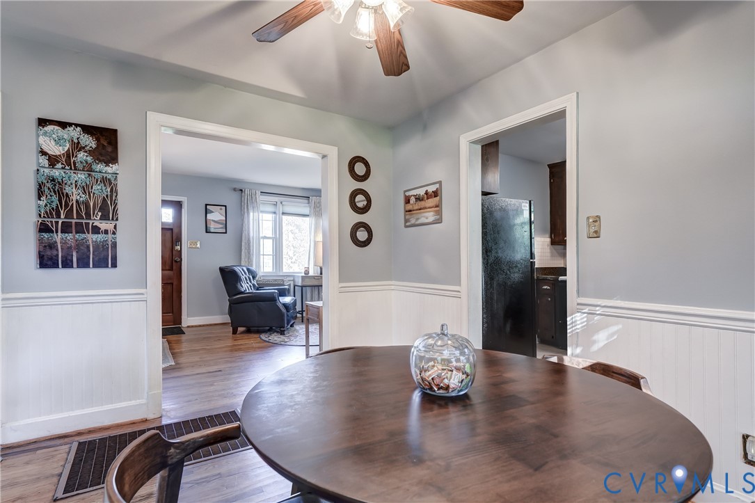 Interior space featuring wood-finish flooring, white wainscoting, and a ceiling-mounted fan
