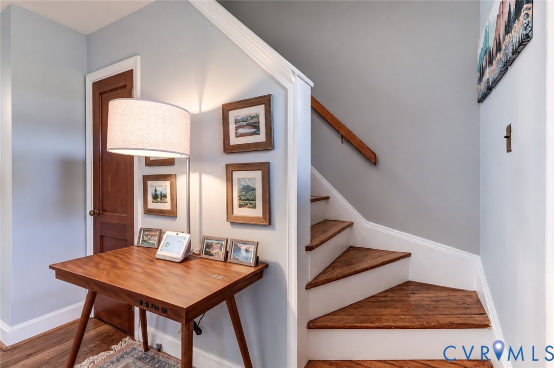 Staircase featuring wood-finish treads, white risers, and a mounted wooden handrail, paired with a solid wood panel interior door