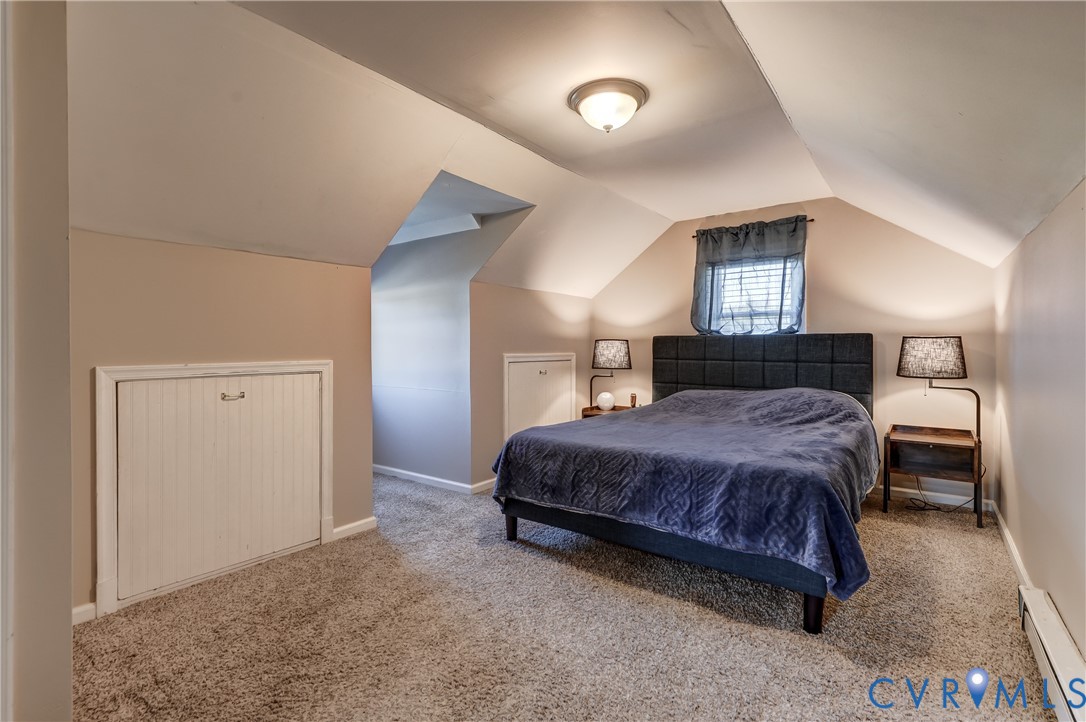 Room featuring vaulted ceilings, neutral-toned wall-to-wall carpeting, and integrated under-eave storage cabinetry