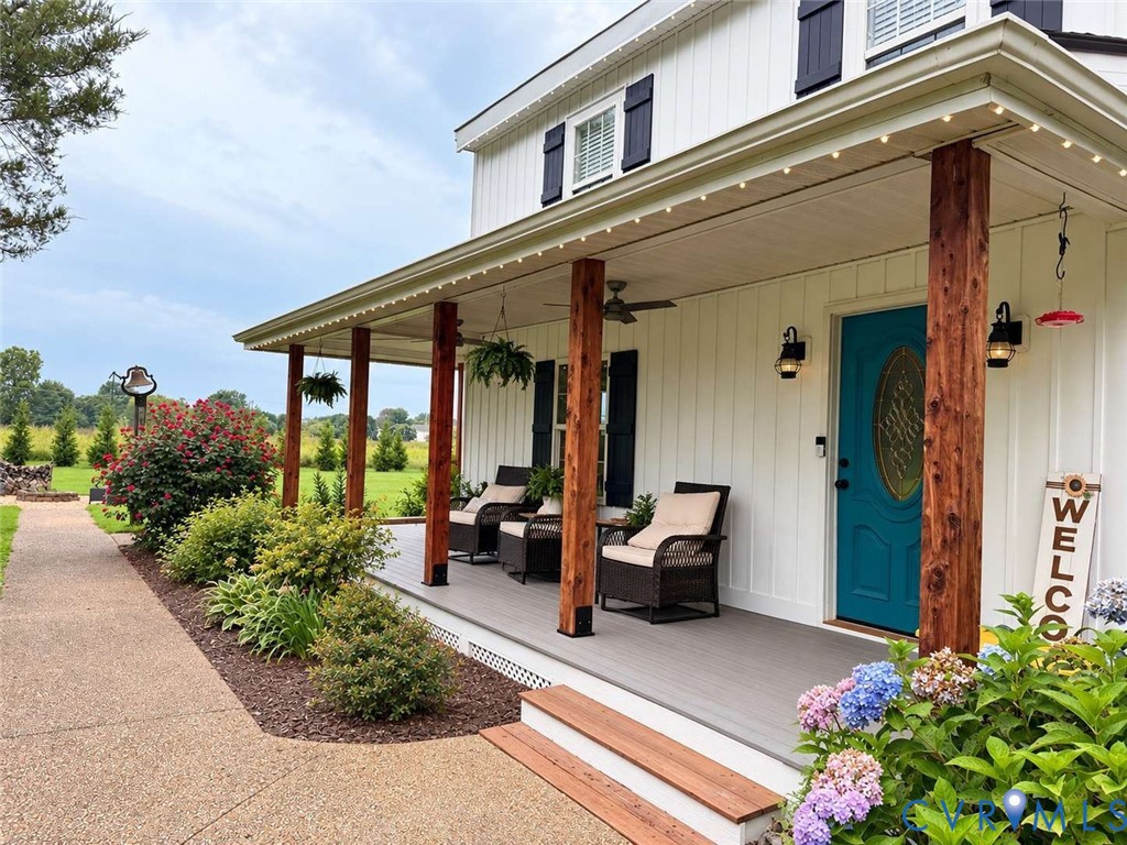 Board and batten siding, wraparound covered porch with wood-finish posts, and a decorative glass-inset entry door