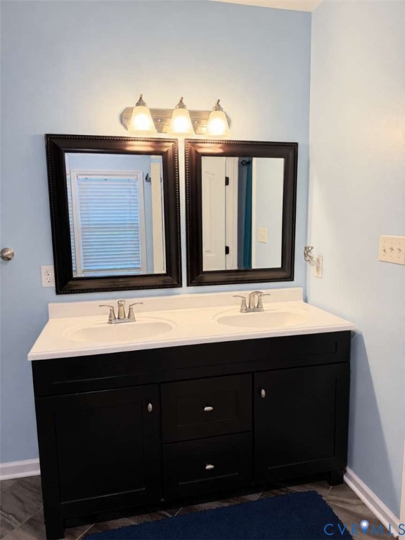 Double vanity featuring a dark-finish base cabinet, integrated dual-basin countertop, brushed-metal hardware, and dual framed wall mirrors with a three-light vanity fixture