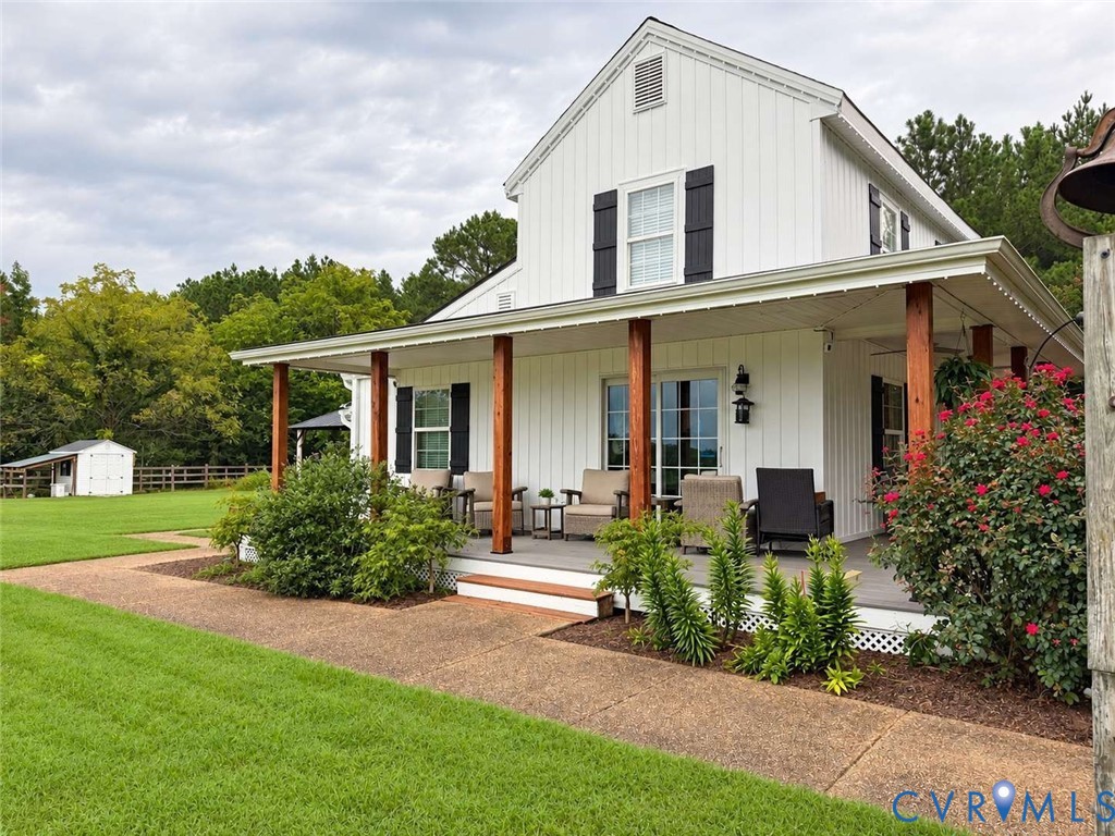 Vertical siding exterior featuring a wraparound porch with stained wood posts, decorative shutters, and expansive lawn space