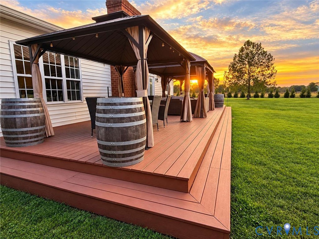 Multi-level composite deck featuring a metal-frame gazebo structure and expansive rear lawn