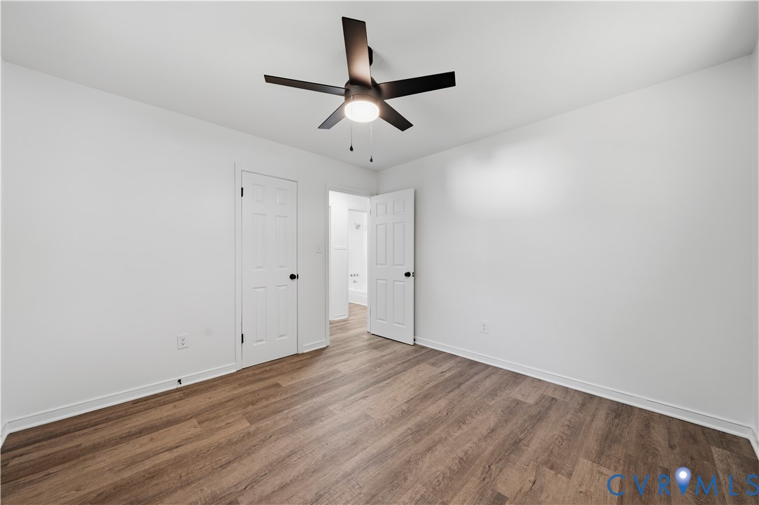 Interior space featuring wood-finish flooring, a five-blade ceiling fan with integrated lighting, and two six-panel doors with matte black hardware
