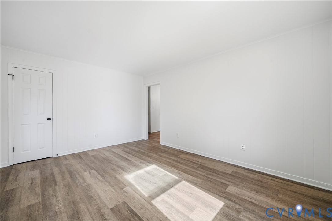 Interior room featuring wood-finish flooring, white paneling, and a six-panel door