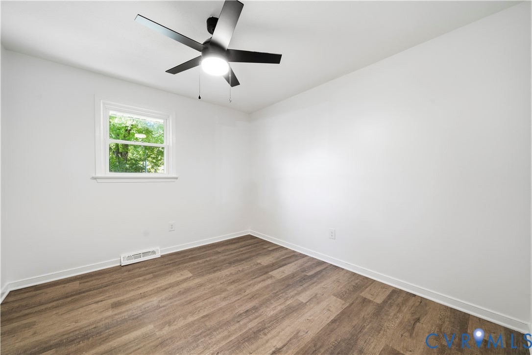 Room featuring wood-finish flooring, a matte black multi-blade ceiling fan with integrated lighting, and a single-pane window