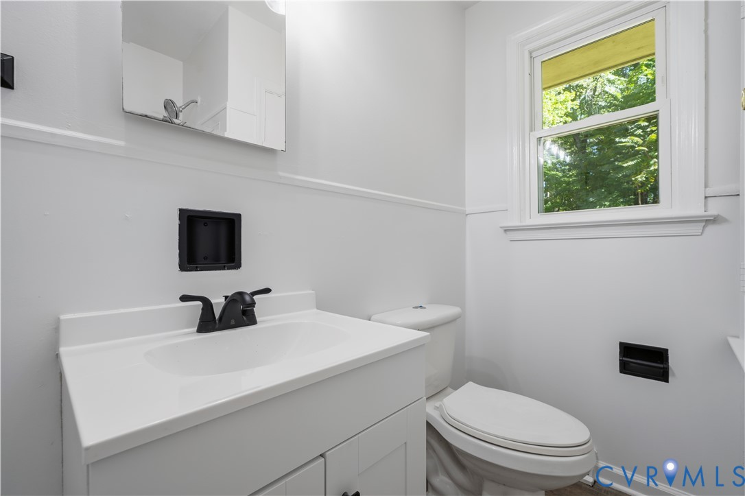 White vanity with a solid surface countertop, integrated sink, matte black faucet, and matching black built-in wall fixtures