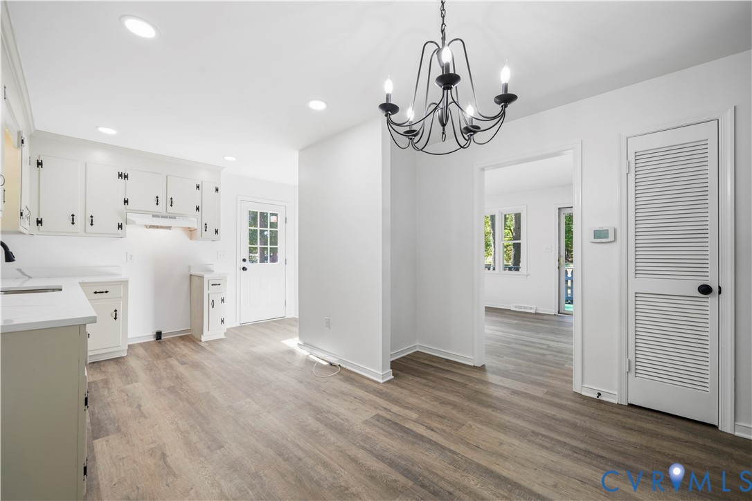 Kitchen featuring white cabinetry, wood-finish flooring, recessed lighting, iron-finish chandelier, and louvered-panel closet doors