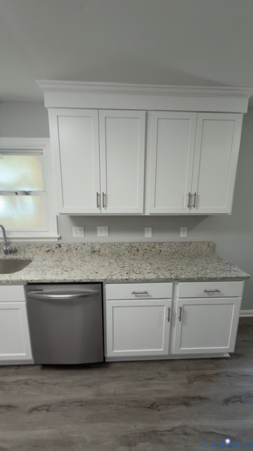 White shaker-style cabinetry with crown molding, stone-finish countertops, stainless steel undermount sink, stainless steel dishwasher, and wood-finish flooring