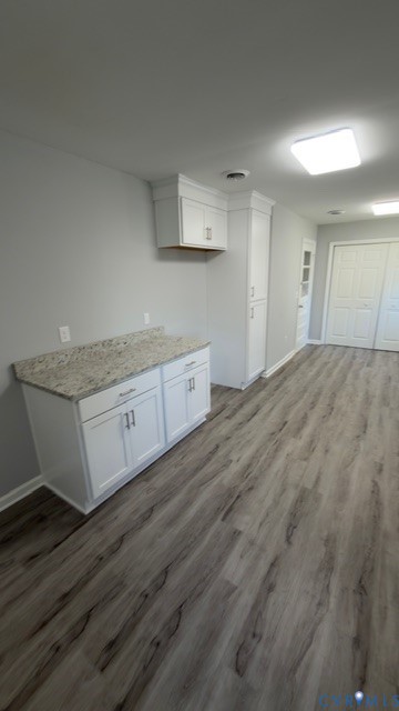 White cabinetry with stone-finish countertops, tall pantry storage, wood-finish flooring, and recessed ceiling lighting