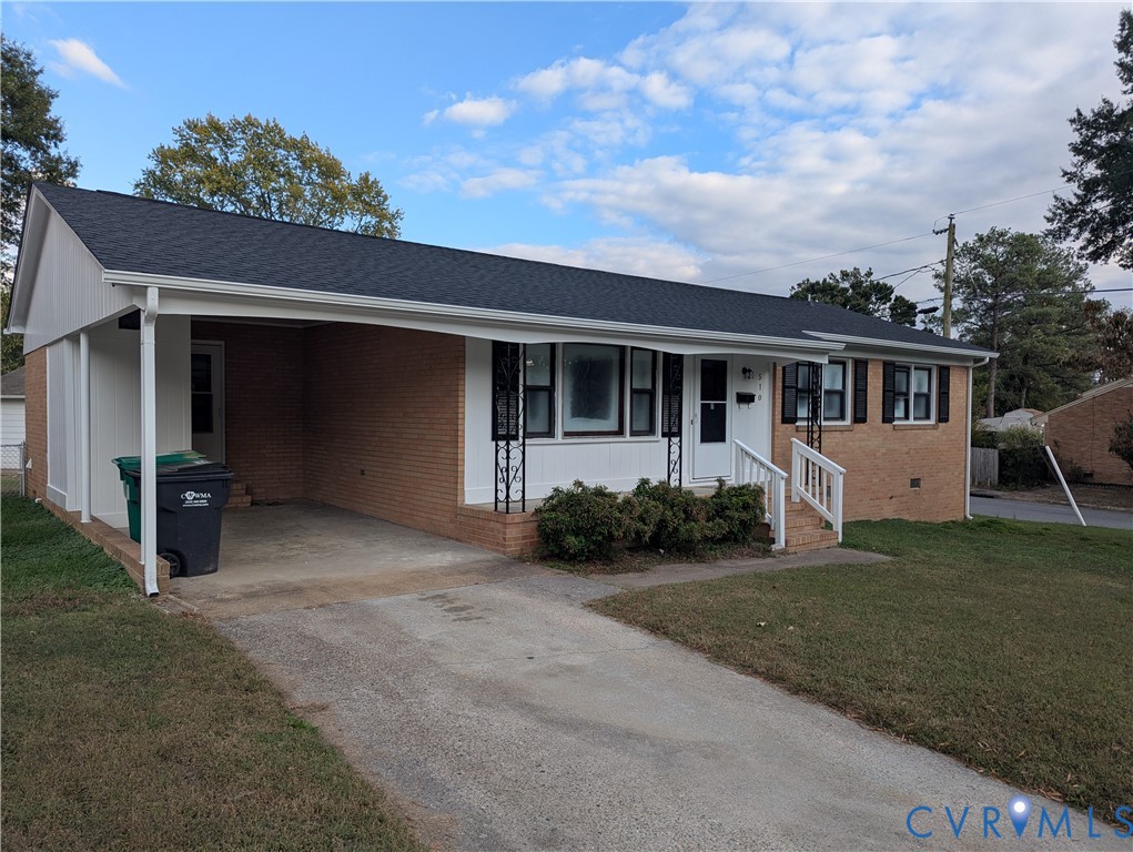 Single-story brick exterior featuring a covered carport, asphalt shingle roof, concrete driveway, and front entryway with metal railings