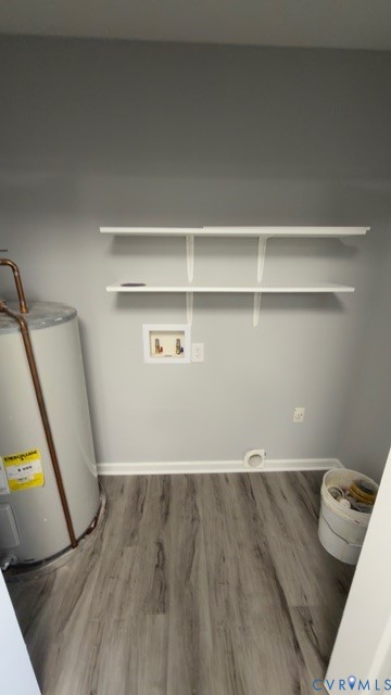 Utility space featuring wood-finish flooring, two wall-mounted white shelves, and water heater