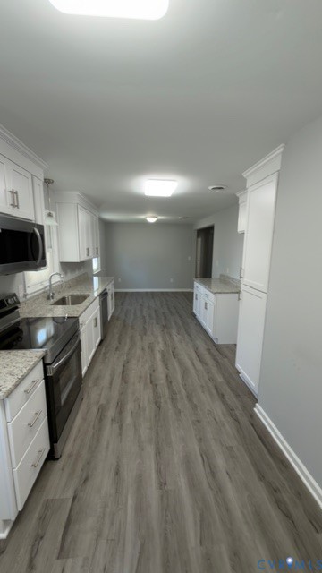 Kitchen featuring white cabinetry, stone-finish countertops, stainless steel appliances, and wood-finish flooring