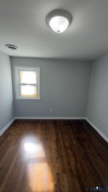 Room featuring dark wood-finish flooring, light gray walls, a single window with white trim, and a ceiling-mounted flush light fixture