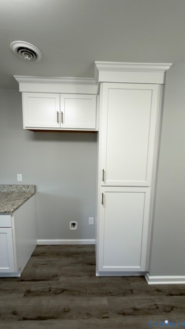 Custom cabinetry with crown molding, stone-surface countertop, and wood-finish flooring