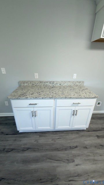 Custom white shaker-style cabinetry featuring satin nickel hardware, light-toned stone-finish countertop with integrated backsplash, and wood-finish flooring