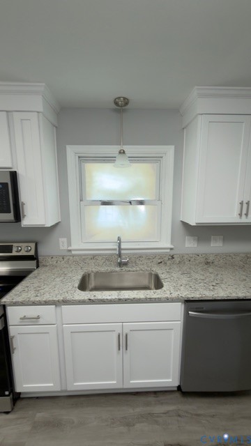 Kitchen featuring white shaker cabinetry, stone-surface countertops, stainless steel undermount sink with gooseneck faucet, brushed-nickel hardware, and pendant lighting