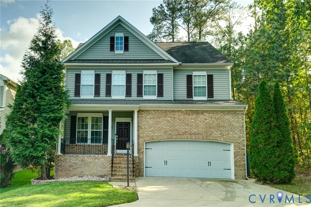 Two-story exterior featuring a mix of horizontal lap siding and lower-level brick masonry, front porch with decorative railing, and attached two-car garage Two-story exterior featuring a mix of horizontal lap siding and lower-level brick masonry, front porch with decorative railing, and attached two-car garage