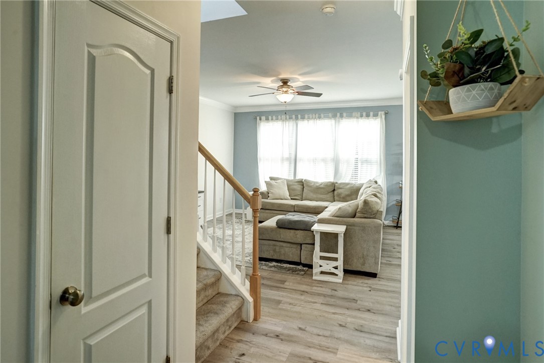 Interior space featuring wood-finish flooring, a ceiling fan with integrated lighting, a staircase with a wooden handrail, and white interior doors