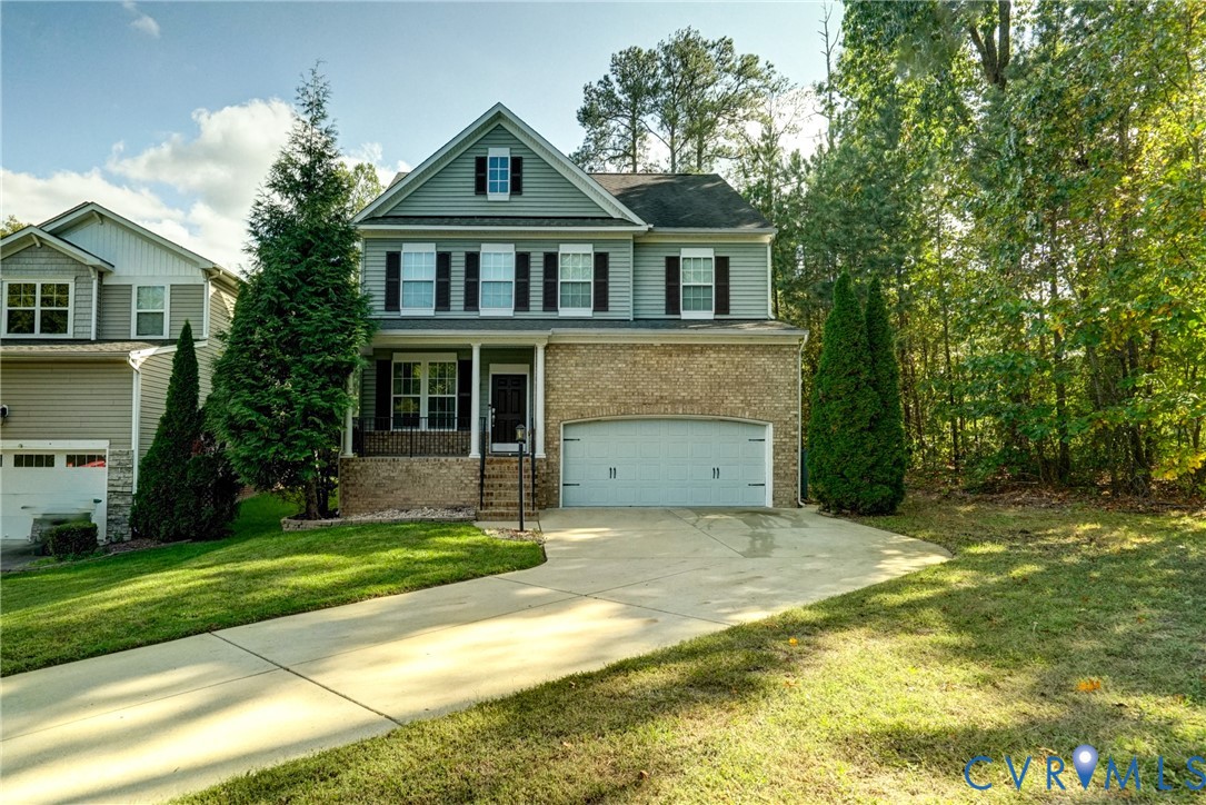 Two-story residence featuring a combination of brick and lap siding, a front-facing attached two-car garage, shuttered windows, and a covered entryway Two-story residence featuring a combination of brick and lap siding, a front-facing attached two-car garage, shuttered windows, and a covered entryway