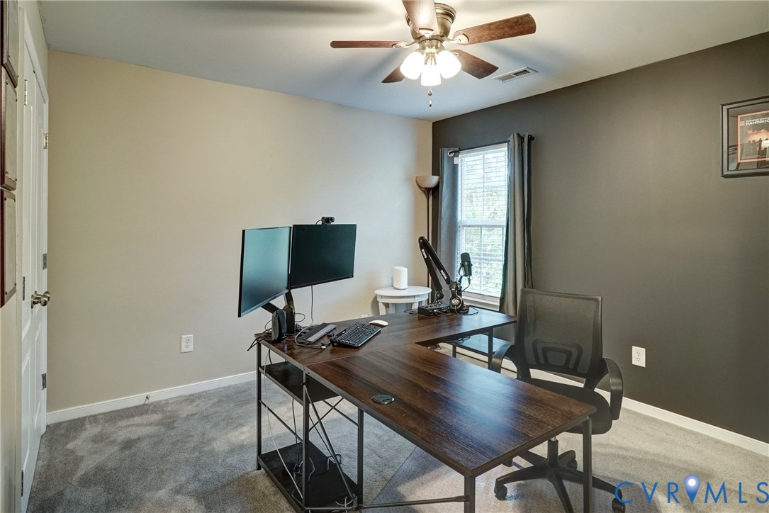 Room featuring neutral wall tones, a dark accent wall, plush carpeting, and a multi-blade ceiling fan with integrated lighting