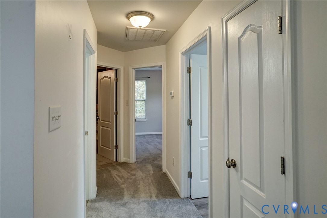 Interior hallway featuring wall-to-wall carpeting, flush-mount lighting, and four-panel interior doors with metallic hardware