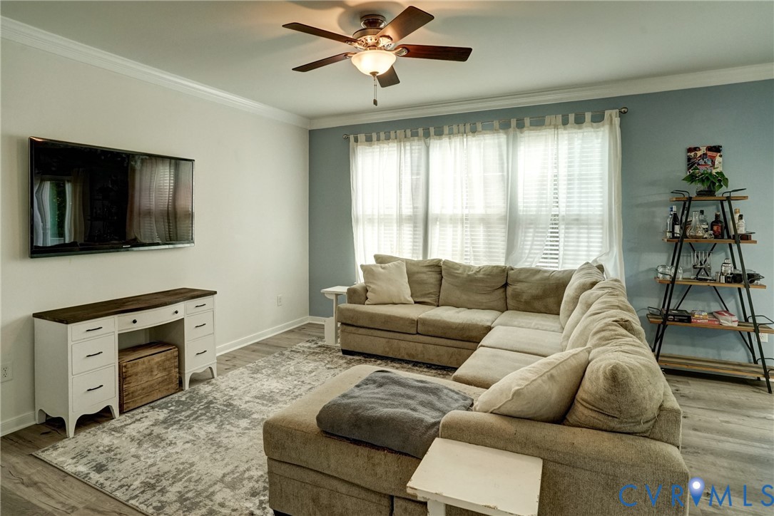 Room featuring wood-finish flooring, a multi-pane window configuration, and a central ceiling fan with an integrated light fixture