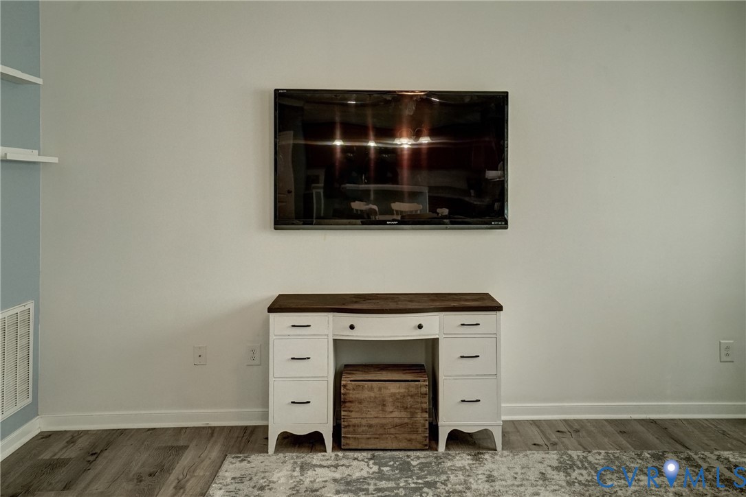 Neutral wall finish featuring wood-finish flooring and wall-mounted shelving