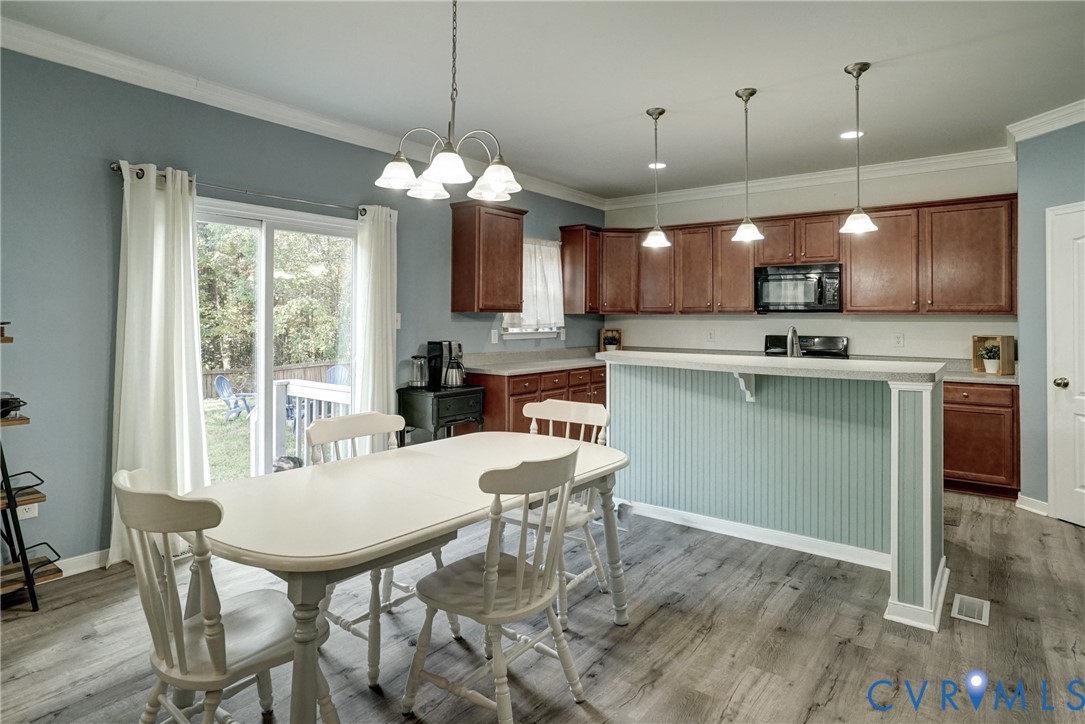 Kitchen featuring stained wood cabinetry, a peninsula with beadboard paneling, wood-finish flooring, recessed lighting, and a multi-light chandelier