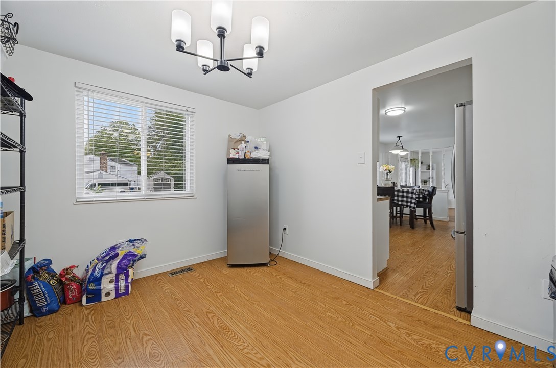 Multi-light chandelier, wood-finish flooring, and window with horizontal blinds